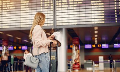 Pasager într-un aeroport verificând panoul de plecări, în contextul creșterii taxelor aeroportuare Spania 2026