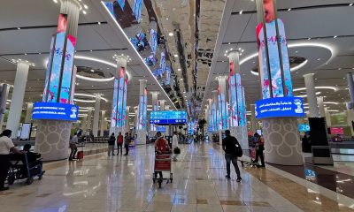Interiorul terminalului Aeroportului Internațional Dubai DXB cu coloane LED și pasageri, hub aerian afectat de restricțiile pentru companiile aeriene străine în 2026