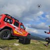 Salvamontist operând o dronă lângă un vehicul Salvamont, ilustrând siguranța pe munte