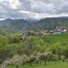 Satul Măgura cu gospodării risipite pe versant și creasta Pietrei Craiului înzăpezită în fundal