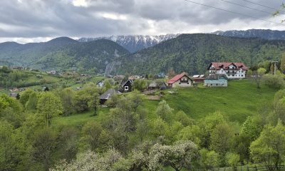 Satul Măgura cu gospodării risipite pe versant și creasta Pietrei Craiului înzăpezită în fundal