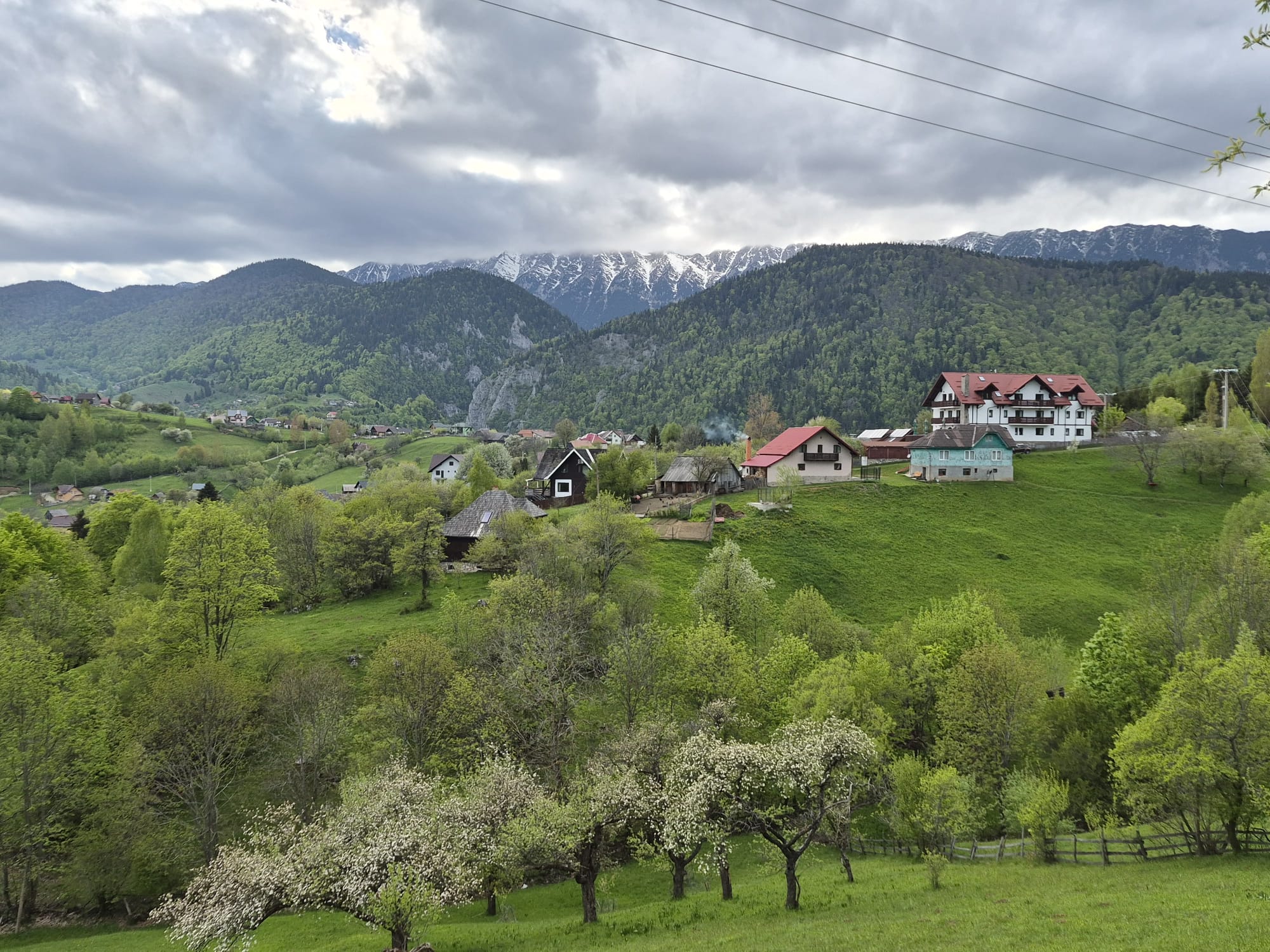 Satul Măgura cu gospodării risipite pe versant și creasta Pietrei Craiului înzăpezită în fundal