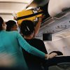 Pasager care așază un troller în compartimentul de deasupra scaunelor, ilustrând regulile Wizz Air privind bagajele de cabină
