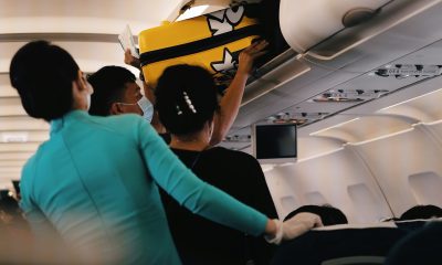 Pasager care așază un troller în compartimentul de deasupra scaunelor, ilustrând regulile Wizz Air privind bagajele de cabină