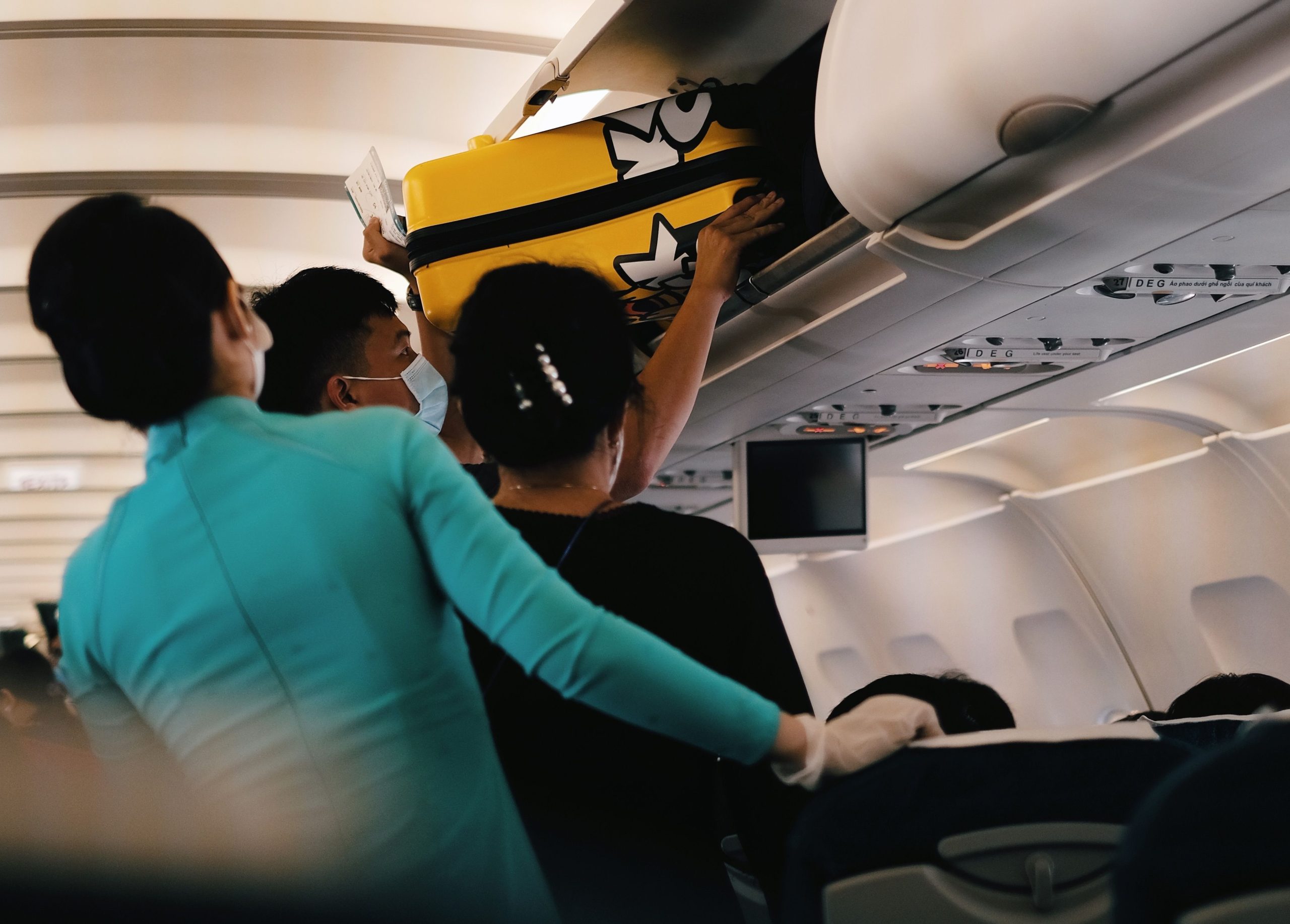 Pasager care așază un troller în compartimentul de deasupra scaunelor, ilustrând regulile Wizz Air privind bagajele de cabină