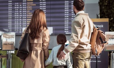 Destinații pentru familii cu copii: părinți și fetiță în fața panoului de plecări dintr-un aeroport