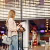 Pasager într-un aeroport verificând panoul de plecări, în contextul creșterii taxelor aeroportuare Spania 2026