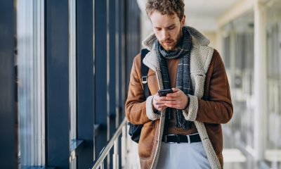 Pasager într-un aeroport folosind aplicația GoVola pe telefon pentru căutarea zborurilor