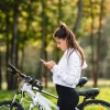 Tânără în pauză lângă bicicletă pe un traseu de cicloturism din România, printre copaci