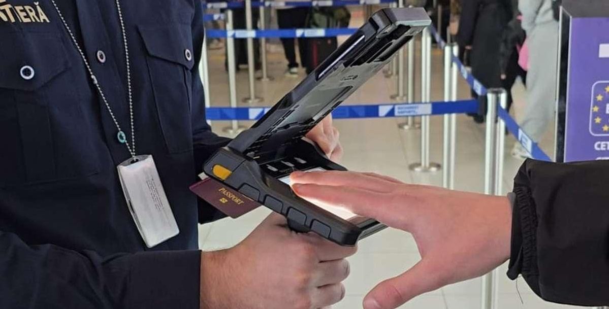 EES frontieră Schengen: polițist de frontieră scanează pașaportul și preia amprentele unui călător
