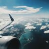 Aripa unui avion de pasageri deasupra unei coaste, ilustrând cele mai aglomerate rute aeriene din 2025