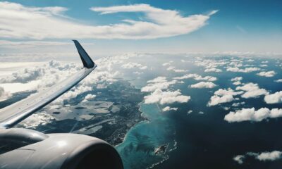 Aripa unui avion de pasageri deasupra unei coaste, ilustrând cele mai aglomerate rute aeriene din 2025