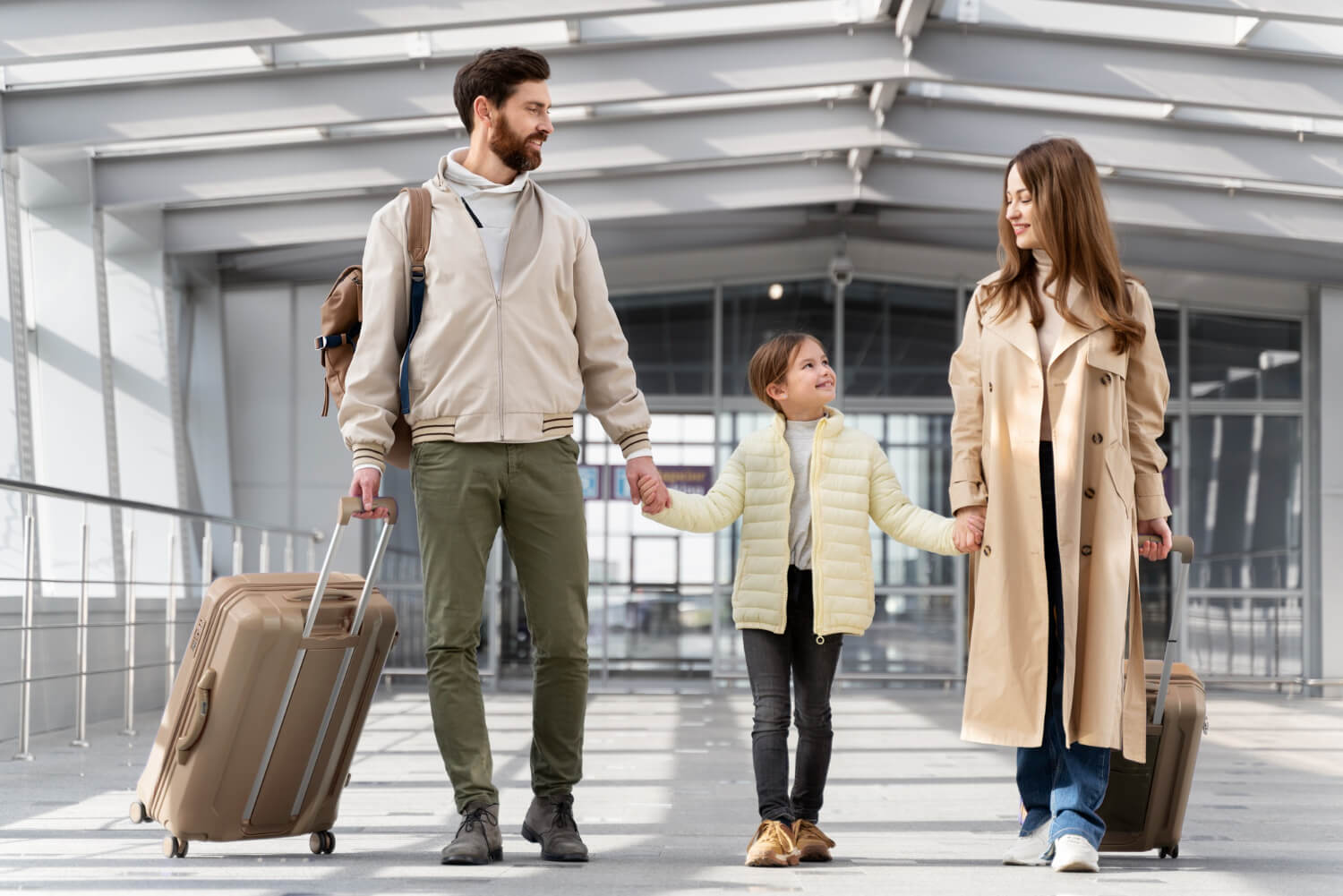 Copil ținut de mână de ambii părinți, cu bagaje, într-un terminal de aeroport, înainte de controlul de frontieră – acte necesare pentru ieșirea din țară a unui minor