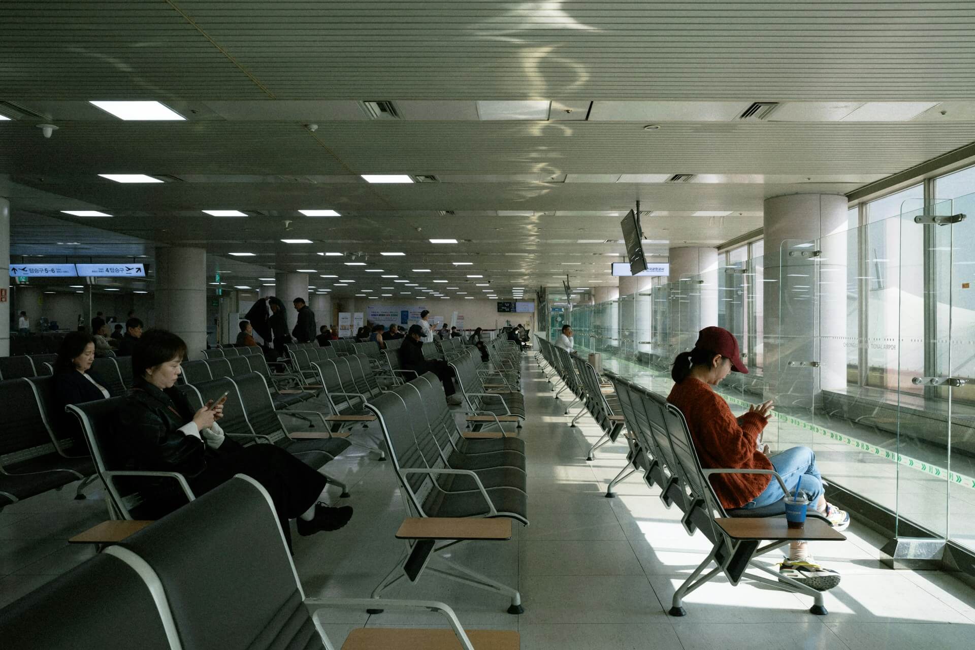 Pasageri care așteaptă în zona porților de îmbarcare a unui aeroport, cu rânduri de scaune goale — despăgubiri zbor întârziat conform Regulamentului 261/2004