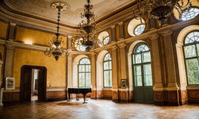 Sala mare a unui castel restaurat, cu candelabre și pian, obiectiv pe rutele turistice în România ale programului România Atractivă