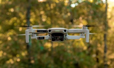 Dronă mică cu cameră, fotografiată în timpul unui zbor cu drona, pe fundal de pădure