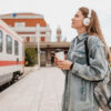Tânără cu rucsac și căști așteaptă pe peronul unei gări, lângă un tren, imagine pentru DiscoverEU 2026
