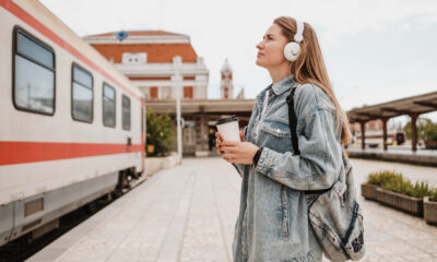 Tânără cu rucsac și căști așteaptă pe peronul unei gări, lângă un tren, imagine pentru DiscoverEU 2026